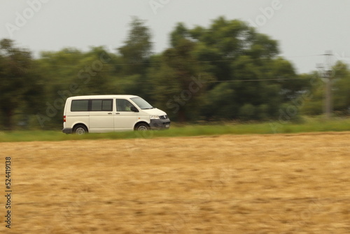 a car driving on the road in the middle of a field, photographed by the panning method © Jitka