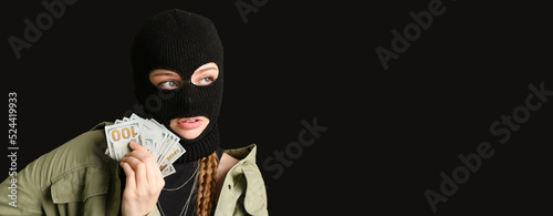 Tableau sur toile Young woman in balaclava and with money on black background with space for text