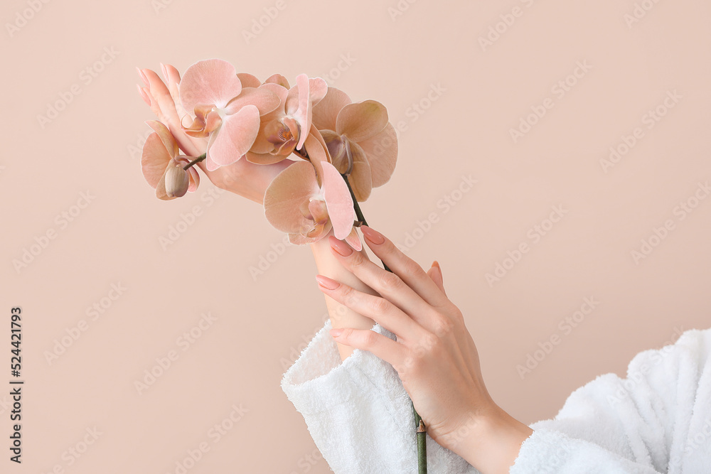 Young woman with beautiful orchid flowers on beige background - obrazy, fototapety, plakaty 