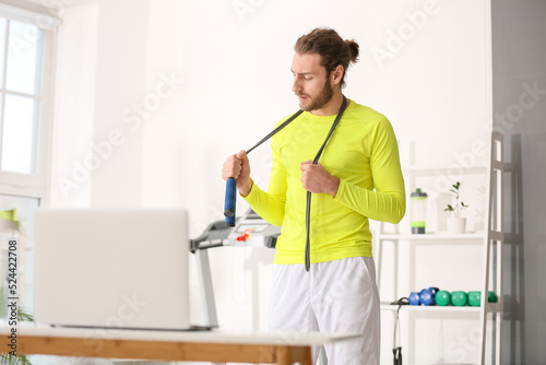 Sporty young man using laptop for online training in gym