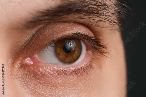 Man with brown eyes on black background, closeup photo