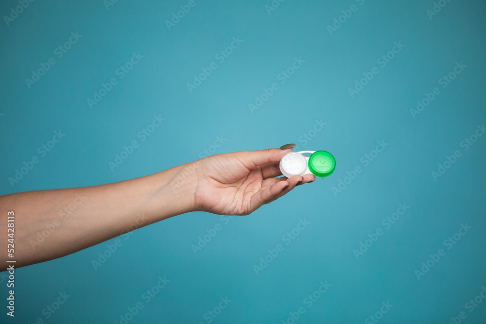 Lady holding case for contact lenses. Closeup image of container for contact lenseson blue background in studio. Lady holding case for contact lenses. Closeup image of container for contact lenseson blue background in studio.