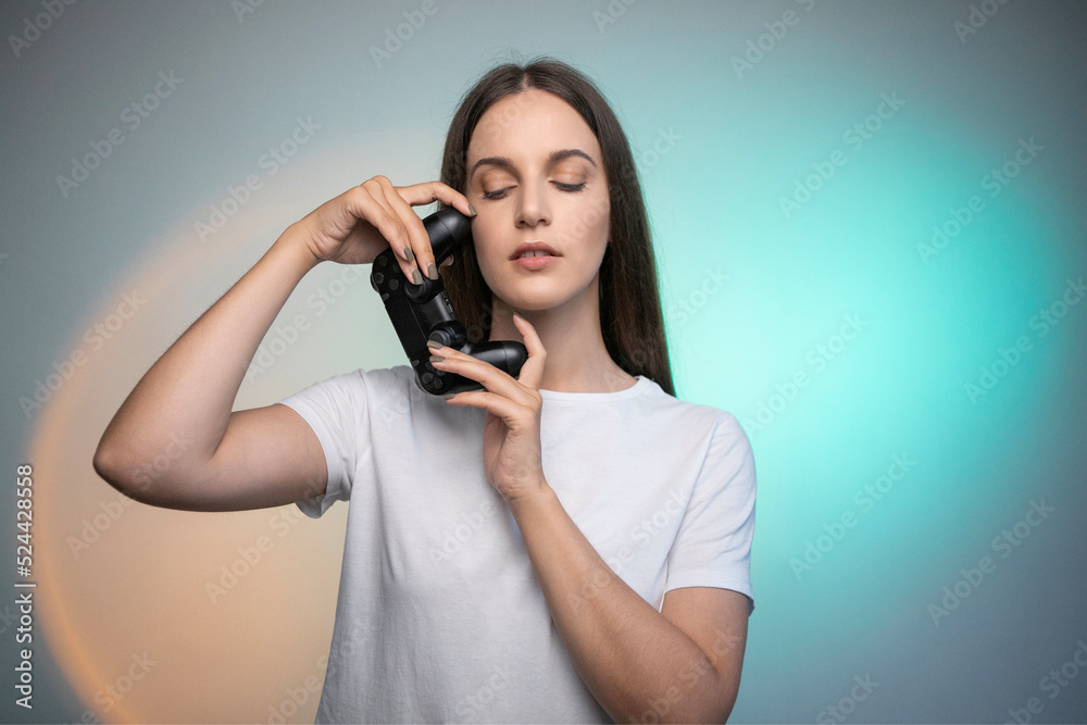 Beautiful woman holding console controller on colorful background. Young adult person enjoying leisure time by playing games with gaming gamepad Beautiful woman holding console controller on colorful background. Young adult person enjoying leisure time by playing games with gaming gamepad