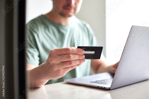 CloseUp von Mann mit Kreditkarte in der Hand benutzt Laptop: Online Shopping, Rechnung bezahlen, Urlaub buchen, Geld Ausgeben, Internet Banking
