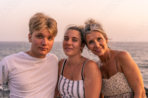 beautiful mother with her two twenty year old sons take a break by the sea at sunset
