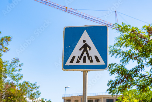 square blue pedestrian crossing sign against the blue sky. Close-up sign regulating the rules of the road in a major city.
