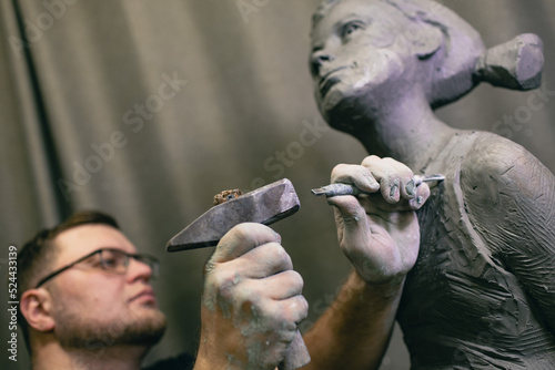 Man sculptor creates sculpt bust human woman sculpture with hammer. Statue craft creation workshop.