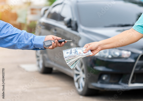 Close up saleman give car key and recieve dollars money from customer.