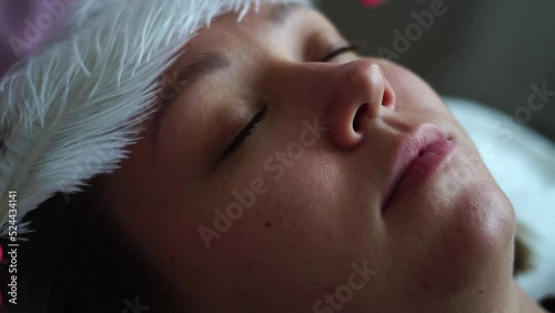  Cosmetology. Facial massage.Massage with feathers. The girl's face is stroked with feathers.Beautiful young girl with a big white feather next to her face. pure soft body products.Perfect fresh skin.