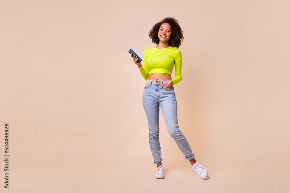 Full size photo of young attractive stylish girl hold phone chatting friend new app isolated on beige color background Full size photo of young attractive stylish girl hold phone chatting friend new app isolated on beige color background