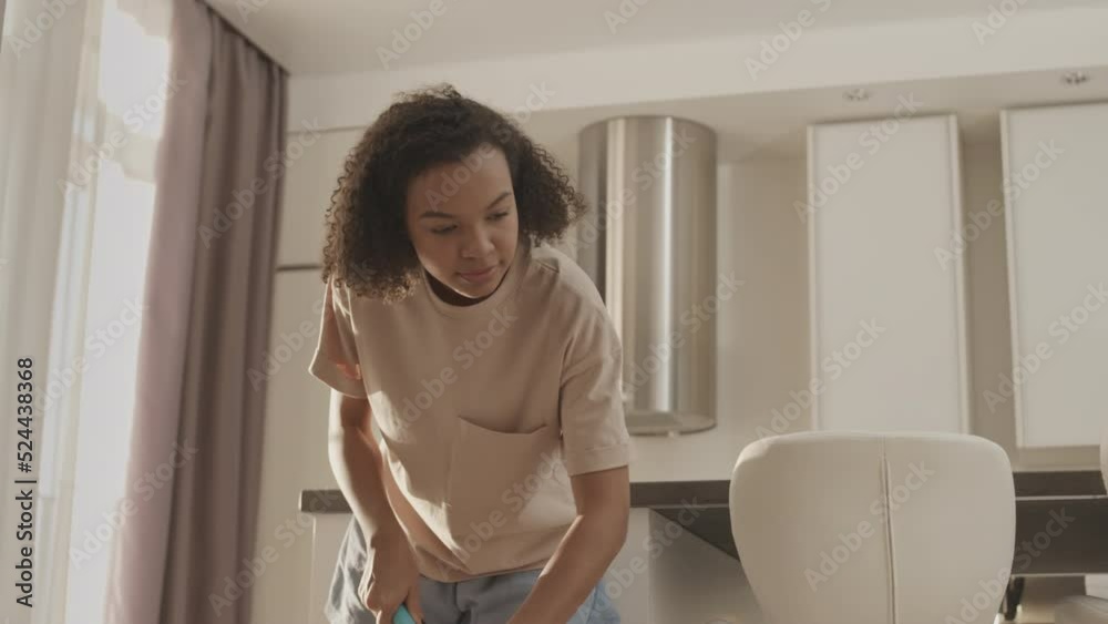 Tilt down slowmo of Biracial girl in homewear mopping floor in her apartment while doing household chores Tilt down slowmo of Biracial girl in homewear mopping floor in her apartment while doing household chores