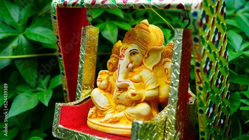 Lord Ganesha idol sitting in decorated swing in Ganesh Chaturthi festival in India. The Elephant god statue with nature background. Also known Vinayaka Chaturthi, Pillaiyar photo