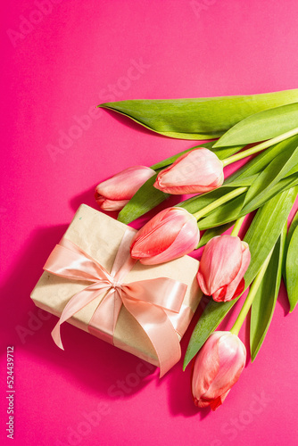 Greeting concept flower composition, a bouquet of pink tulips, and a gift. © FuzullHanum