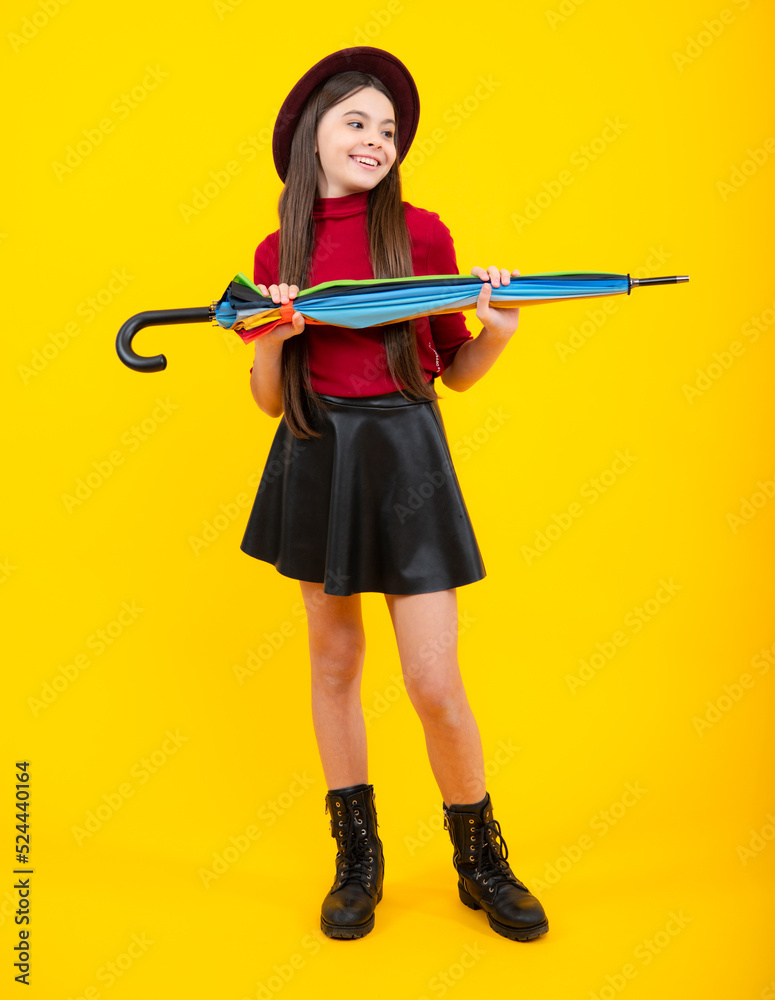 Fashion autumn kids weather, full length. Child teenager girl with umbrella in autumn skirt, sweater, boots and hat isolated on yellow studio background. Autumn trendy clothes. Fashion autumn kids weather, full length. Child teenager girl with umbrella in autumn skirt, sweater, boots and hat isolated on yellow studio background. Autumn trendy clothes.