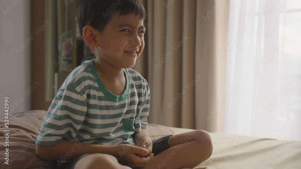 Asian boy Secretly playing while practicing meditation on the bed at home. Asian boy Secretly playing while practicing meditation on the bed at home.