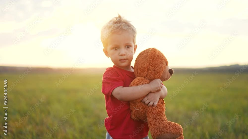 portrait of a baby boy with a toy teddy bear in his hands on nature in ...