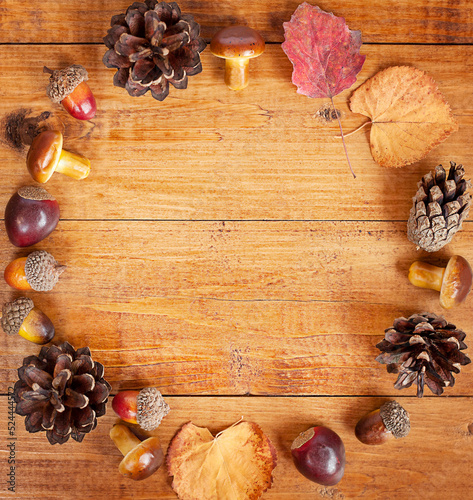 circle of leaves, cones, acorns and mushrooms on a wooden background