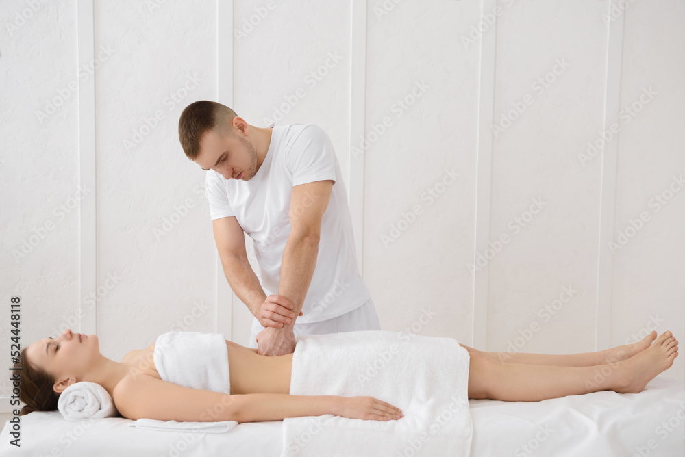 Close up of osteopath doing manipulative massage on woman abdomen on white background, copy space Close up of osteopath doing manipulative massage on woman abdomen on white background, copy space