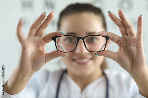 Female ophthalmologist doctor holding glasses in ophthalmology clinic