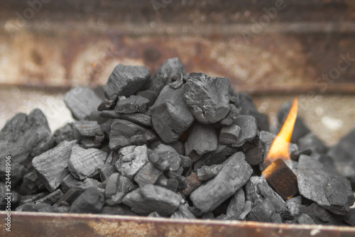 Close-up of black coal and flame in the folding portable brazier. Preparation for cooking food on the grill.