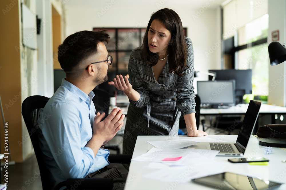 Fototapeta premium Colleagues arguing in office. Angry businesswoman yelling at her collegue.