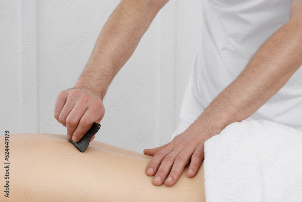 Obraz premium Young pretty woman having back guasha acupuncture treatment, white background. Copy space, closeup