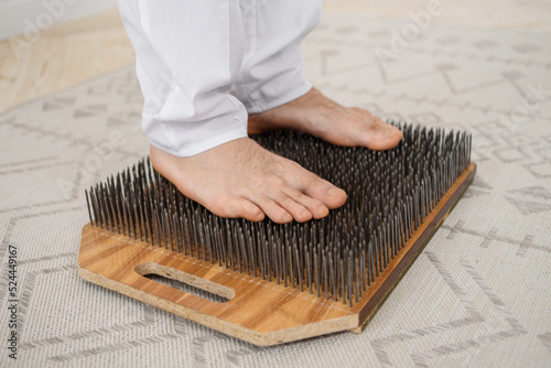 Young man practicing of standing on nails, copy space.  Person legs on sadhu board yoga meditation foot massage