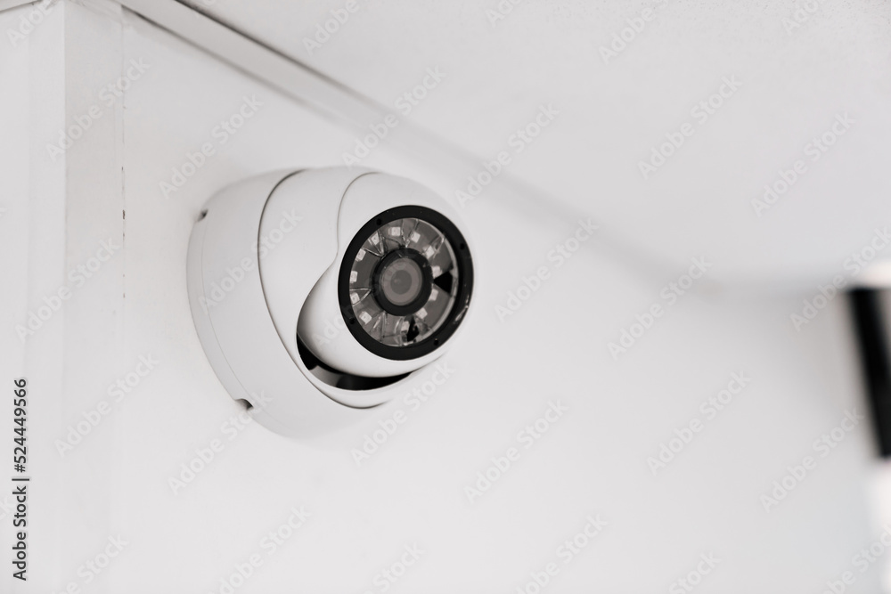 CCTV camera with broken glass on a white wall under the ceiling. CCTV camera with broken glass on a white wall under the ceiling.