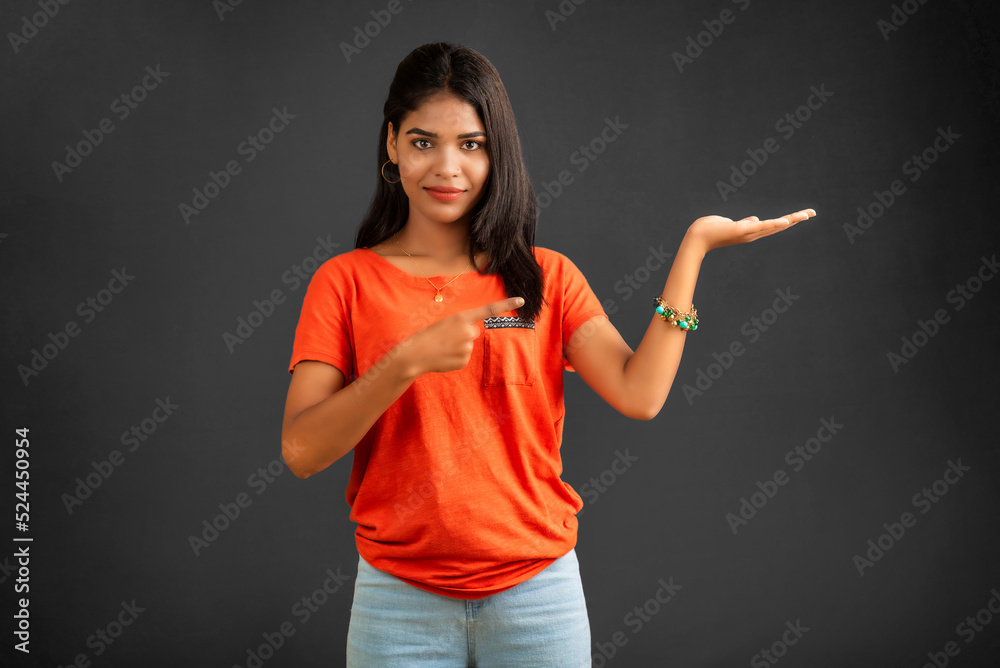 Portrait of a successful cheerful young girl holding and presenting something on hand with a happy smiling face. Portrait of a successful cheerful young girl holding and presenting something on hand with a happy smiling face.
