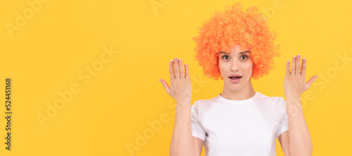 surprised freaky woman in curly clown wig with raised hands, surprise. Woman isolated face portrait, banner with copy space.