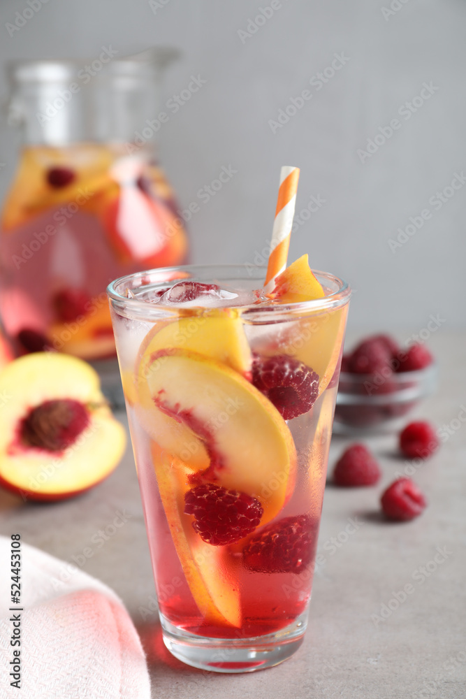 Delicious peach lemonade with soda water and raspberries on grey table. Fresh summer cocktail Delicious peach lemonade with soda water and raspberries on grey table. Fresh summer cocktail