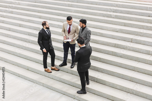Business people outdoor meeting. A group of men in suits stands against the backdrop of the urban steps of a large staircase. Working break. Teamwork and career advancement. Successful promotion