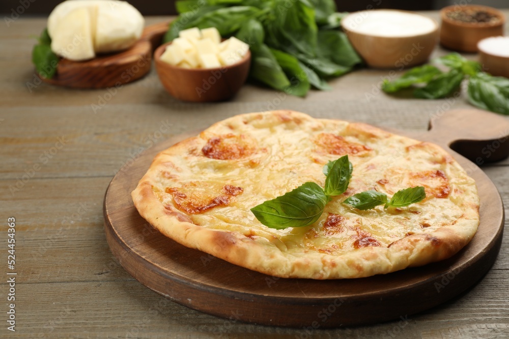 Delicious khachapuri with cheese and basil on wooden table Delicious khachapuri with cheese and basil on wooden table