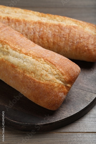 Tasty baguettes on wooden table, closeup. Fresh bread