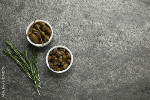 Tasty capers and rosemary on grey table  flat lay. Space for text