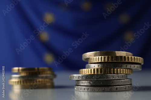 Many different coins on table against European Union flag, closeup. Space for text