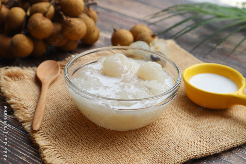 Sticky rice boiled in syrup with longan and coconut milk dressing on wood table - Thai dessert called Kao Nioew Piak LamYai Sticky rice boiled in syrup with longan and coconut milk dressing on wood table - Thai dessert called Kao Nioew Piak LamYai