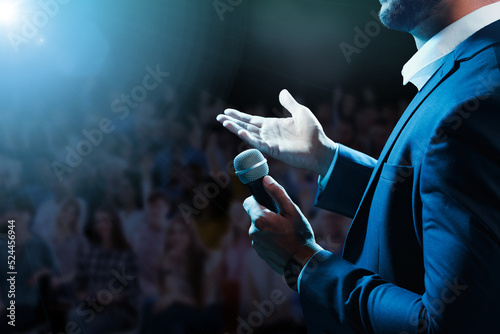 Fotografie Motivational speaker with microphone performing on stage, closeup