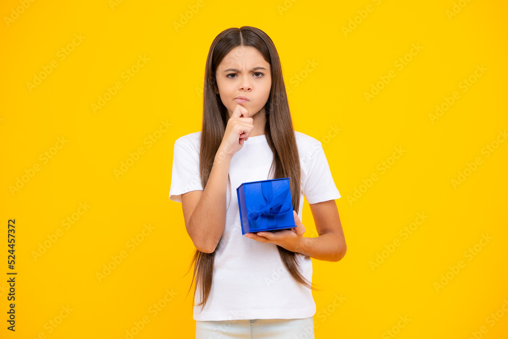 Child with gift present box on isolated studio background. Gifting for kids birthday. Thinking face, thoughtful emotions of teenager girl. Child with gift present box on isolated studio background. Gifting for kids birthday. Thinking face, thoughtful emotions of teenager girl.