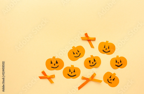 Greeting card for halloween. Paper pumpkins with orange bows on beige background, copyspace