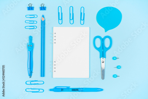 Blue school supplies and blank notepad on blue background photo