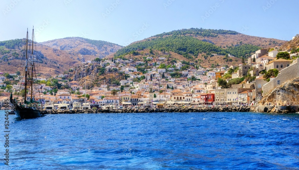 A view of the beautiful Greek island, Hydra. There is a fishing boat on the foreground and some local architecture on the background. The view is from the sea as the cruise ship embarked in Hydra.
