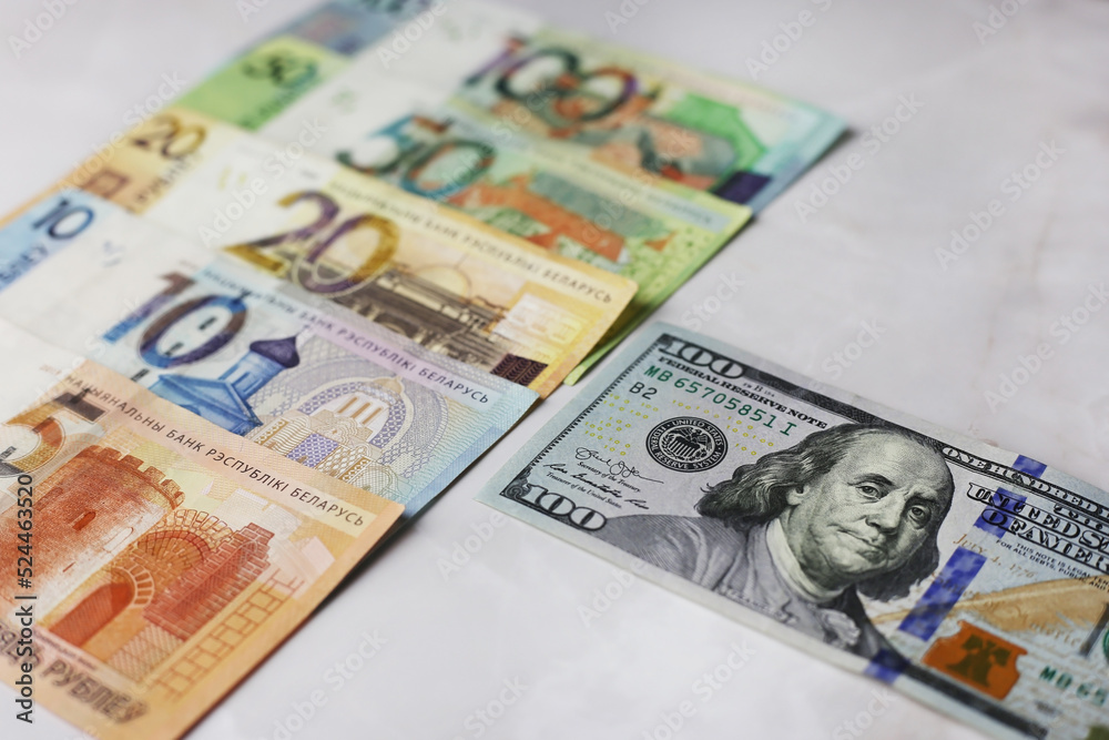 Banknotes in denominations of 100,50,20,10.5 belarusian rubles and 100 dollars on an grey background Banknotes in denominations of 100,50,20,10.5 belarusian rubles and 100 dollars on an grey background