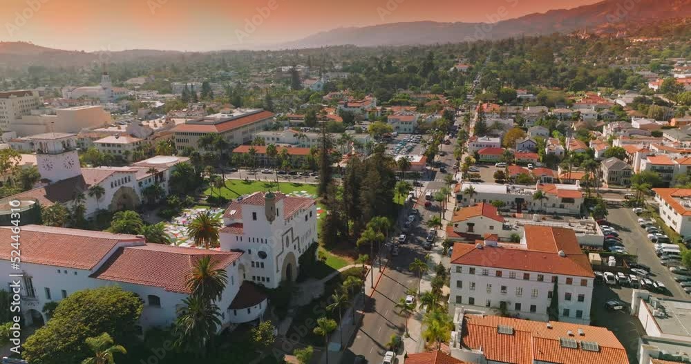 Lovely white houses with orange roofs, numerous cars on the streets and parking lots. Beautiful architecture and hills of Santa Barbara at backdrop of pink skies. Lovely white houses with orange roofs, numerous cars on the streets and parking lots. Beautiful architecture and hills of Santa Barbara at backdrop of pink skies.
