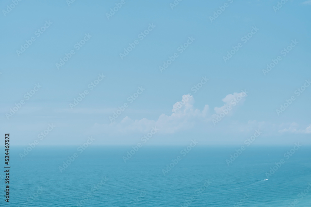 Obraz premium Sunny sky with clouds and a calm sea on a midday background. Soft blurry focus. Hot summer vacation, pastel colors and sun glare. Abstract blur poster or advertising banner