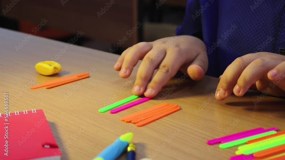 Close-up of a student's hand moving math colored sticks with his finger. Schoolboy is on a mission. Educational school concept.Elementary and middle school. UHD 4K. Close-up of a student's hand moving math colored sticks with his finger. Schoolboy is on a mission. Educational school concept.Elementary and middle school. UHD 4K.