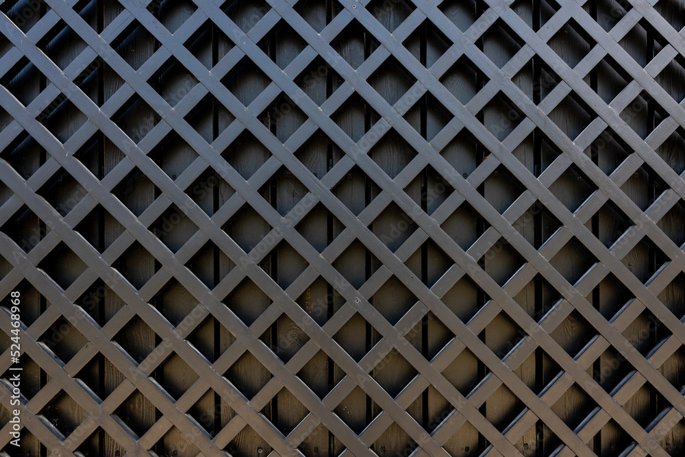 Fragment of wooden fence made of painted black boards. Wooden diagonal lattice. Copy space. Fragment of wooden fence made of painted black boards. Wooden diagonal lattice. Copy space.