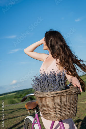 brunette woman with long hair and lavender flowers in blurred wicker basket.