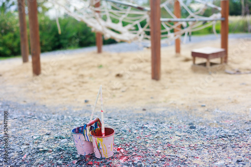 Two colorful cans and brush laydown on black rock in playground, sumer camp learning photo