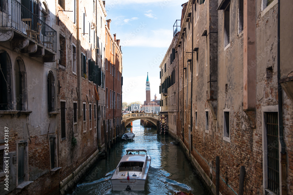 View of a narrow canal and boat and ancient buildings at Venice, Veneto, Italy.